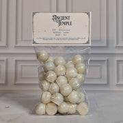 Ancient Temple wax melt drops in a sealed cello bag with a navy and gold topper card, on white marble