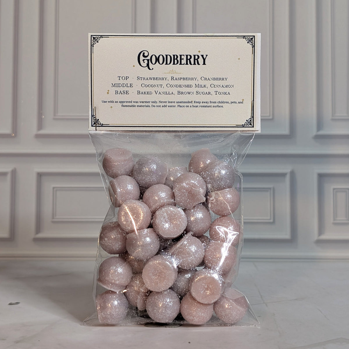 Goodberry wax melt drops in a sealed cello bag with a navy and gold topper card, on white marble