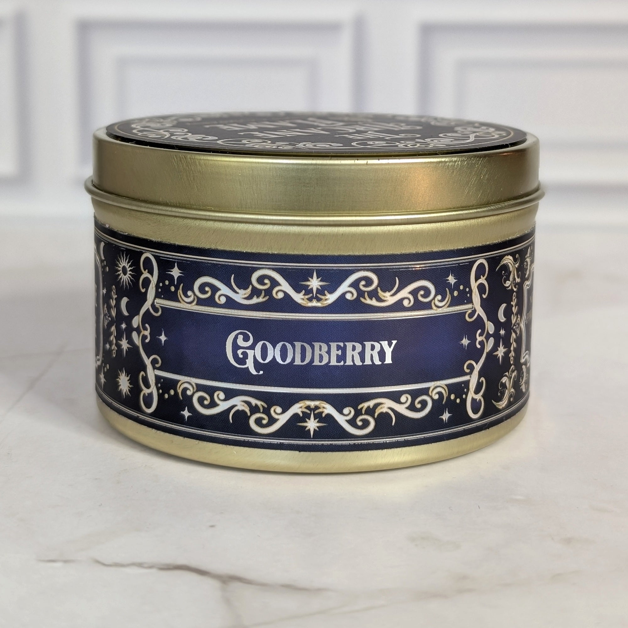 Goodberry 8oz soy candle in a gold tin with a navy and gold foil label, on white marble